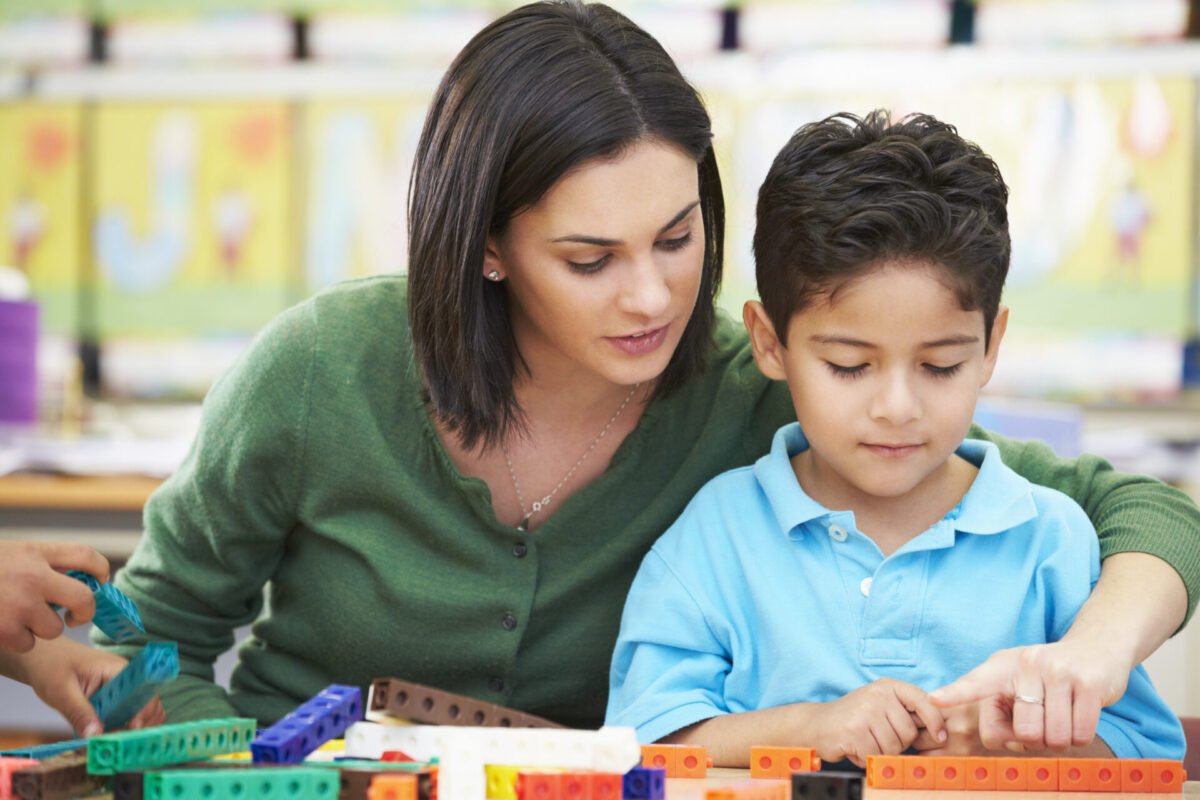 Math teacher tutoring young boy with manipulatives